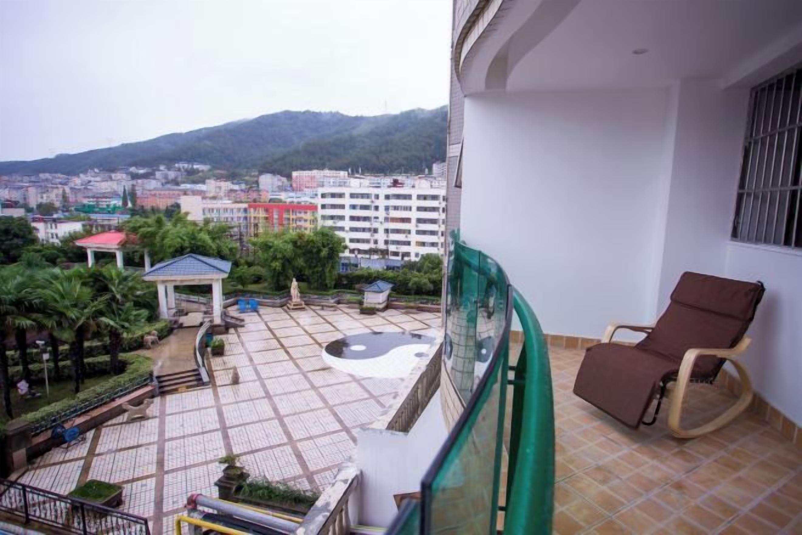 A balcony with a view of a cityscape, a chair, and a small garden area.