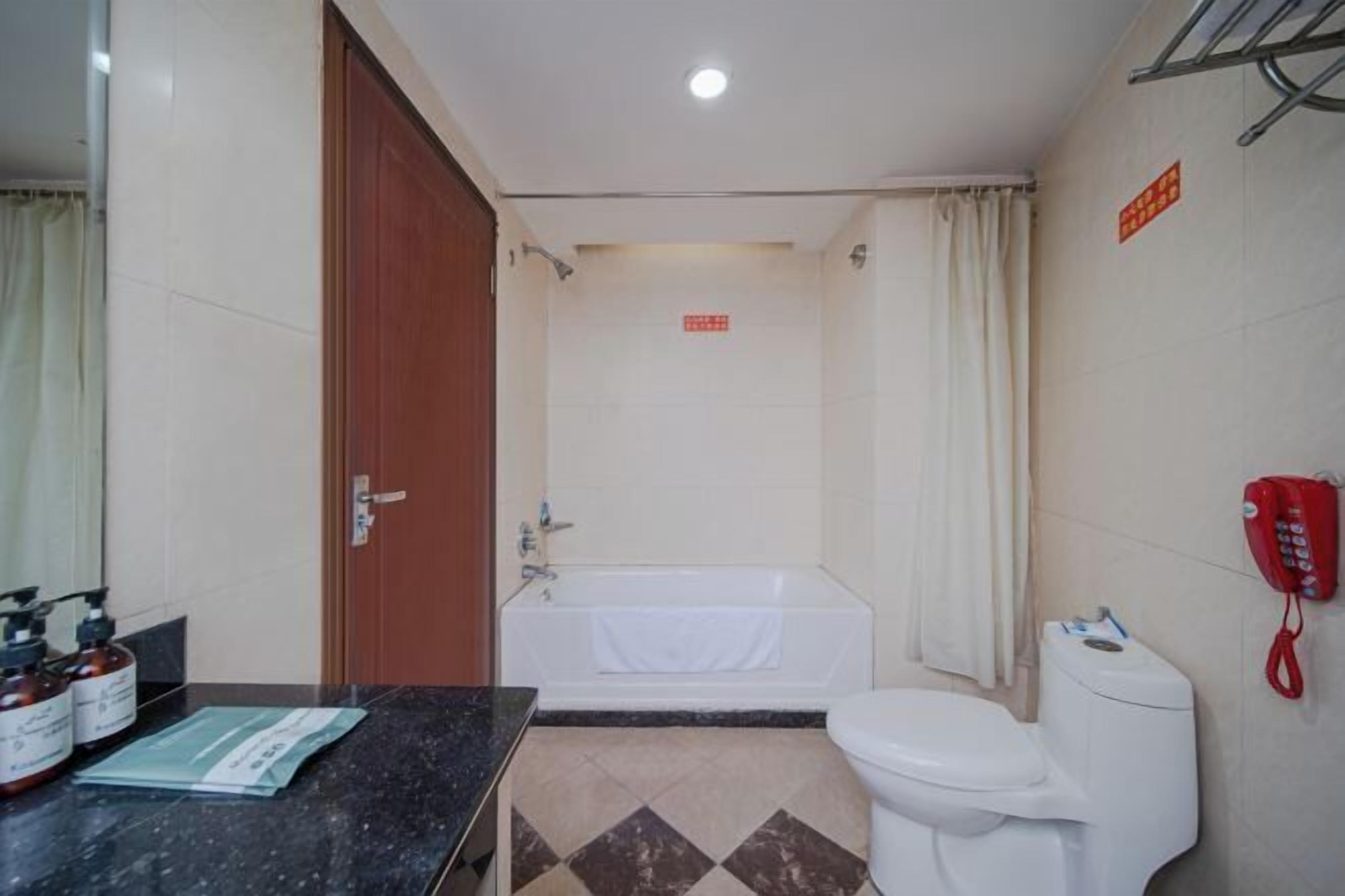 Een badkamer met een bad, toilet en wastafel met zeepdispensers.