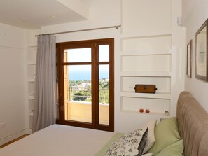 Une chambre à coucher avec un lit, une fenêtre avec des rideaux, un balcon et une vue sur le paysage.