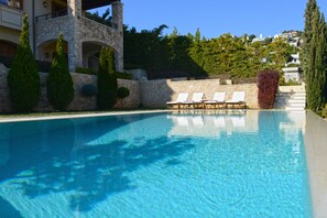 Une piscine aux eaux cristallines, dotée de chaises longues et d’une architecture en pierre.