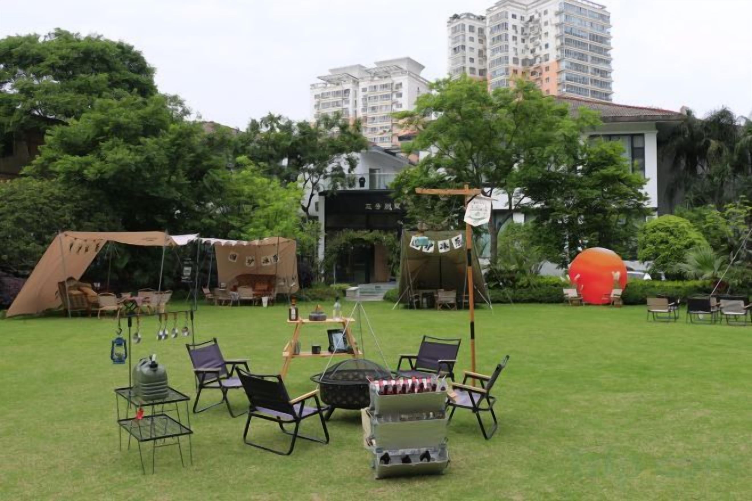 An outdoor seating area with tables and chairs, a tent, and a large inflatable structure.