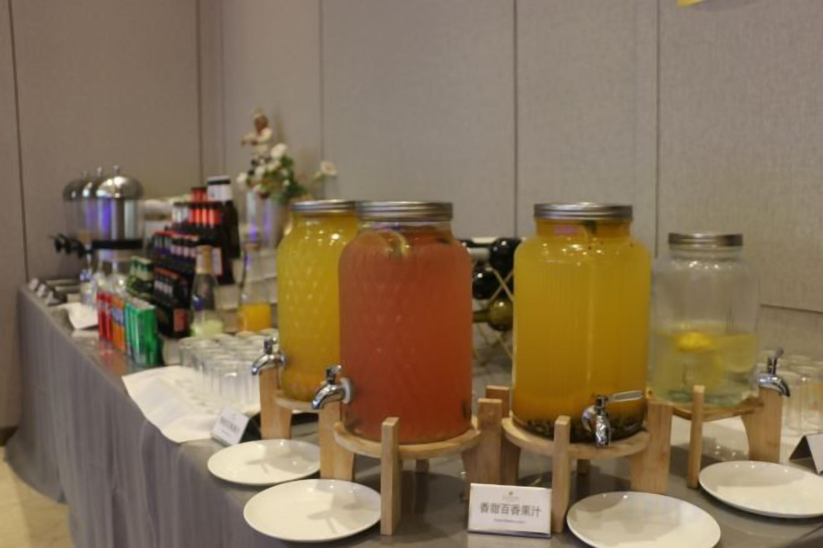 A buffet table with various food and drink options, including jars of beverages and a sign indicating the type of food available.