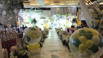 A corridor with floral decorations and balloons, leading to a seating area.