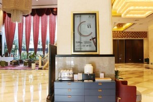 Un vestíbulo de hotel con una recepción, un reloj enmarcado y un mostrador de registro.