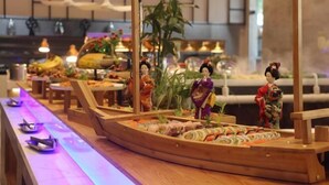 Sushibaari, jossa on puusta valmistettuja, veneen muotoisia tarjoilutelineitä ja perinteinen japanilainen sisustus.