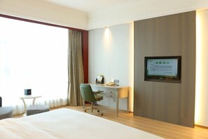 A hotel room with a bed, a desk, a chair, a small table, and a television mounted on the wall. - Sanhe Grand New Century Hotel Pingyang (Pingyang)