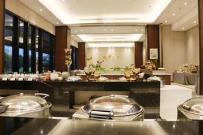 Een hotel lobby met een receptiebalie, een buffetgedeelte en zitplaatsen.