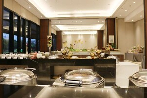 Un vestíbulo de hotel con recepción, zona de buffet y asientos.