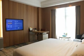 A hotel room with a large bed, a desk, a chair, a television on the wall, and a window with curtains. - Sanhe Grand New Century Hotel Pingyang (Pingyang)