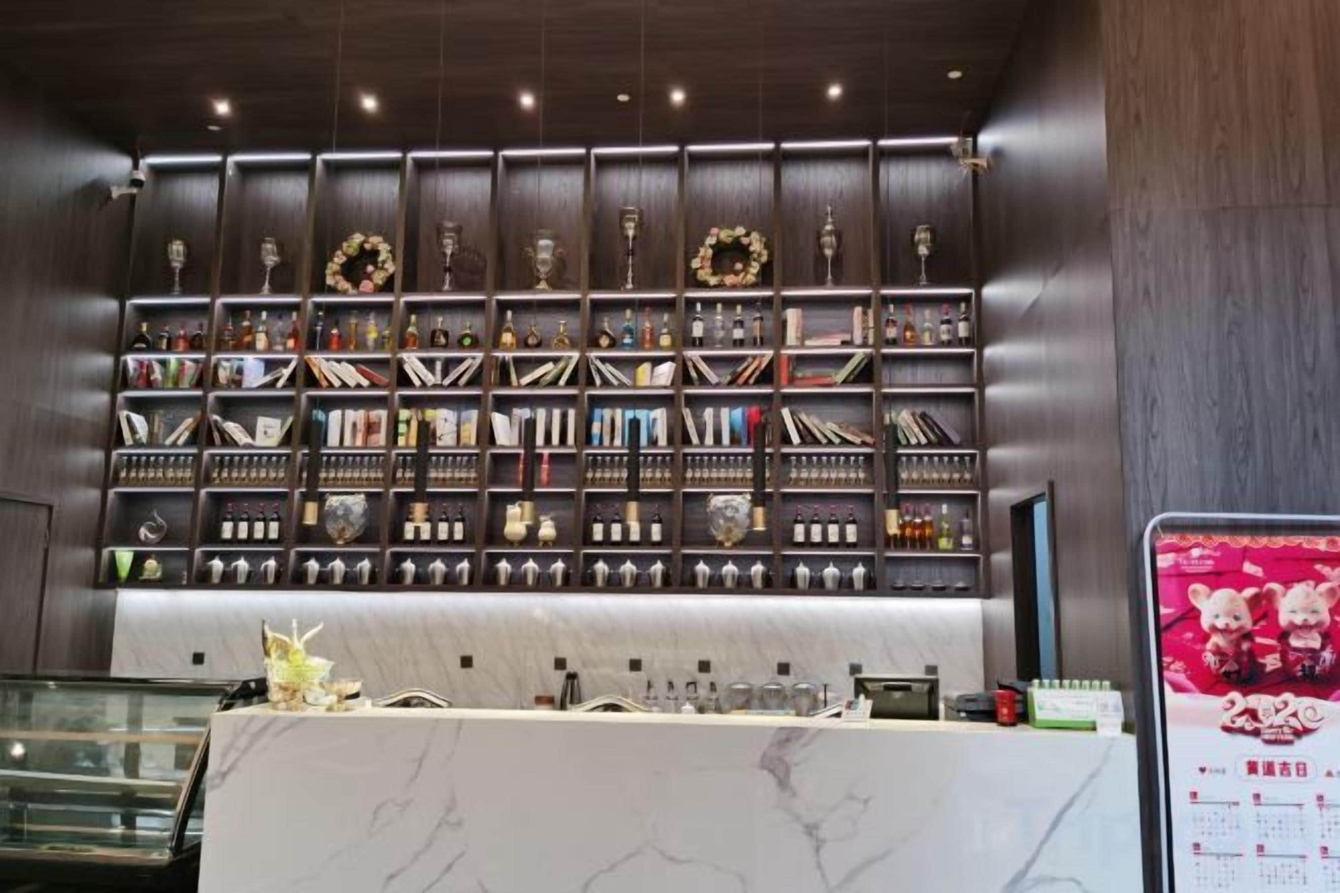 A bar area with shelves of bottles and glasses, a marble counter, and a menu board.