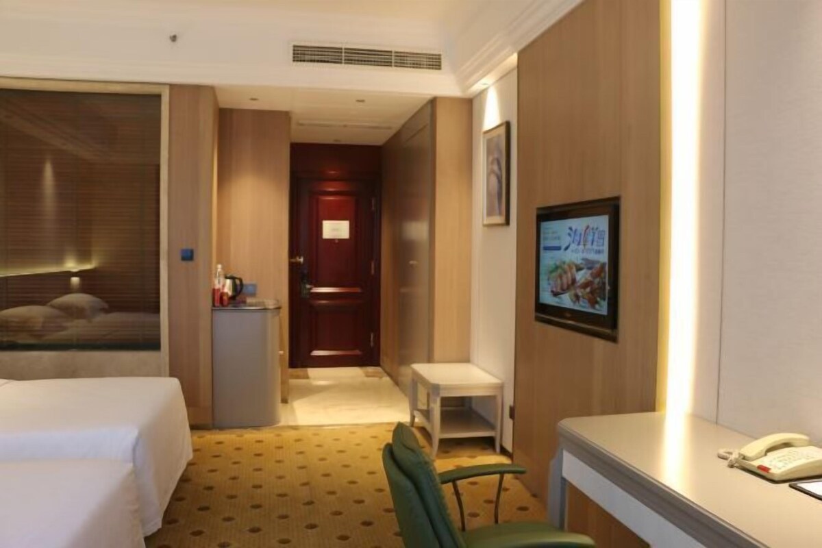 A hotel room with a bed, a desk, a chair, a phone, and a television.