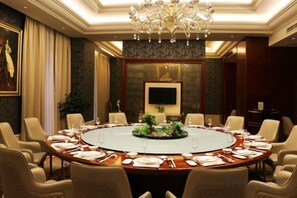 Een vergaderzaal met een ronde tafel, stoelen en een kroonluchter.