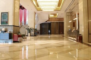Un vestíbulo amplio con mostrador de recepción, zona de estar y una escalera que conduce a los pisos superiores.