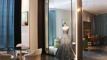 A hotel lobby with a mannequin in a dress, a seating area, and a view into a room.
