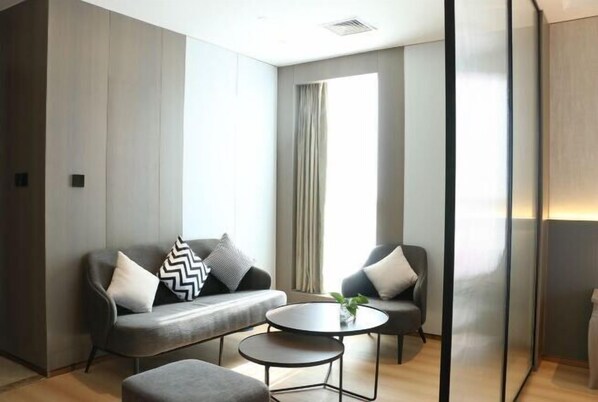 A modern room with a grey sofa, two armchairs, a small round table, and a large window with curtains. - Sanhe Grand New Century Hotel Pingyang (Pingyang)