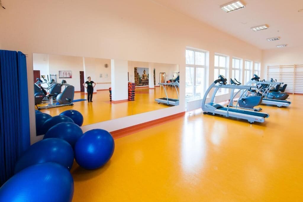 Un gimnasio con equipamiento para ejercicio, una persona de pie y una estatua de Buda.