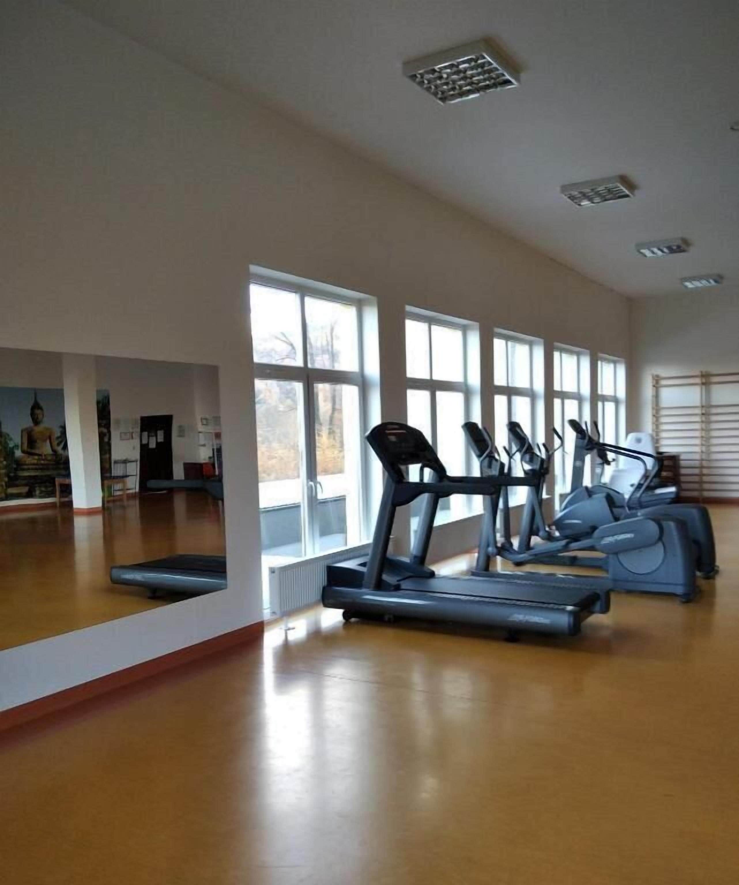 Une salle de sport spacieuse, dotée de grandes fenêtres, de tapis de course et de vélos d’appartement.