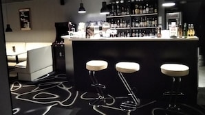 Un bar con taburetes, estantes llenos de botellas y una barra.