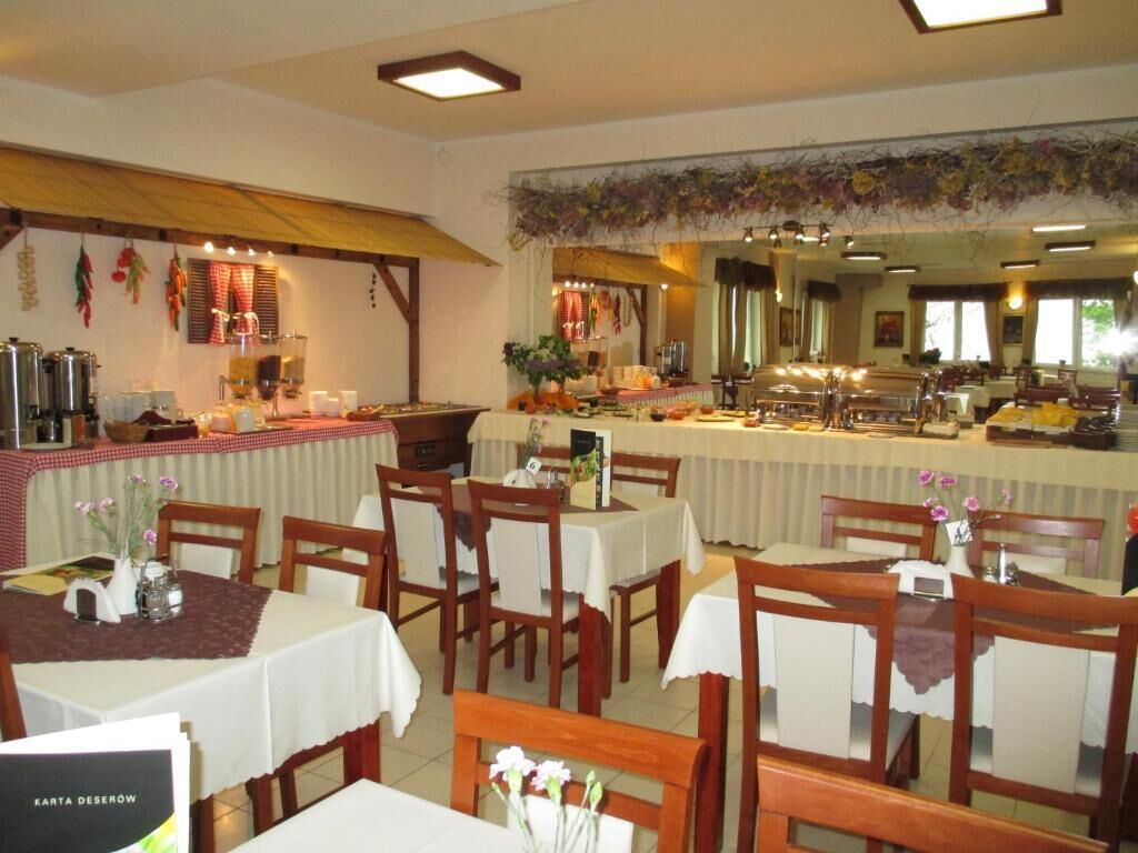 A restaurant with wooden chairs and tables, a buffet area, and a kitchen in the background.