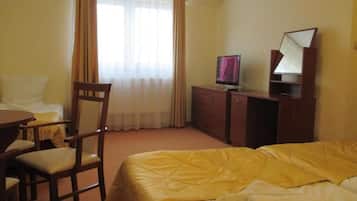 Una habitación de hotel con cama, escritorio, silla, televisor y espejo.