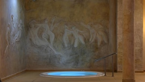 Un área de spa con un mural de pared de piedra, un jacuzzi y una barandilla metálica.