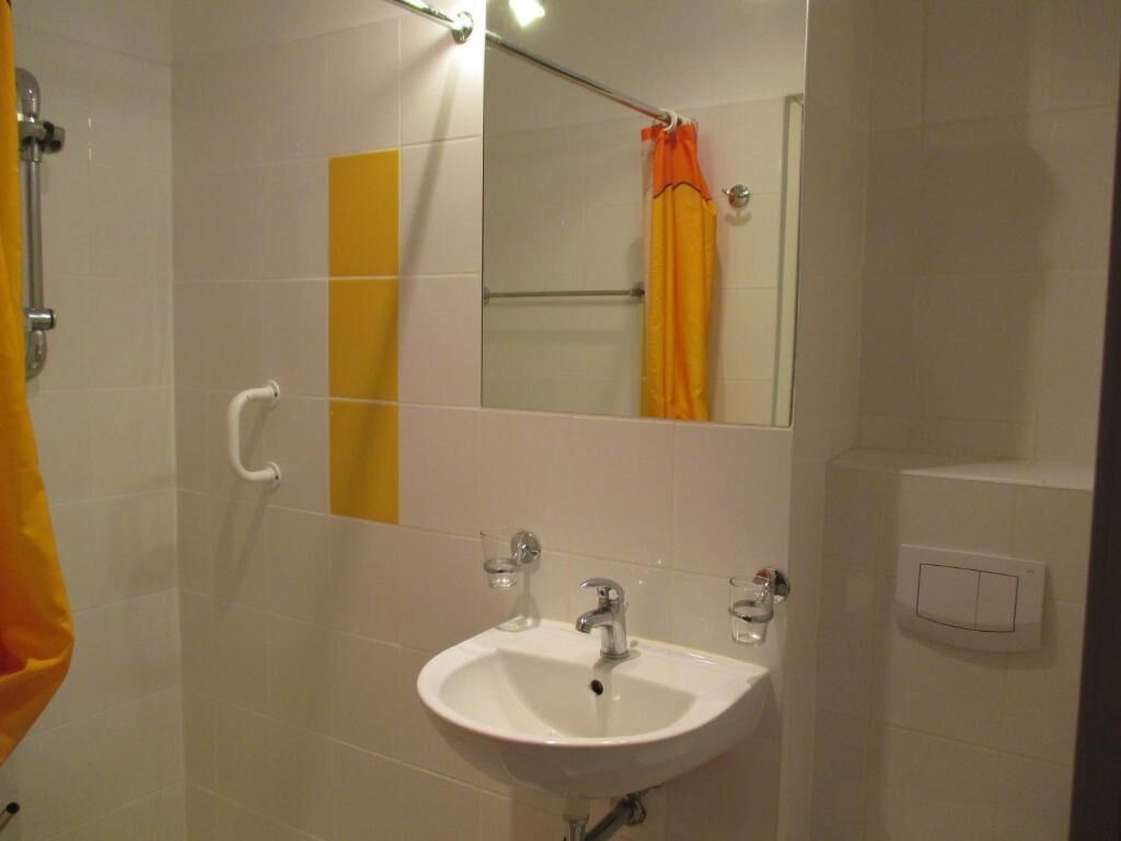 Een badkamer met een wit wastafel, een spiegel en een douchegordijn.