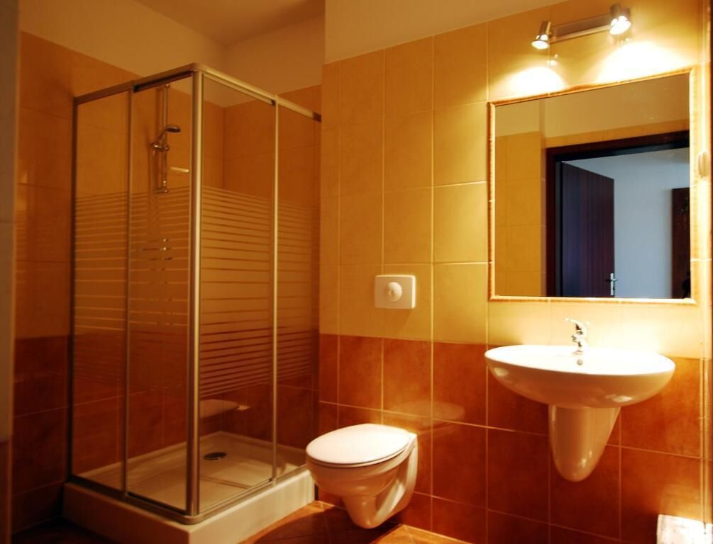 Ein Badezimmer mit Duschkabine, Toilette und Waschbecken mit Spiegel darüber.