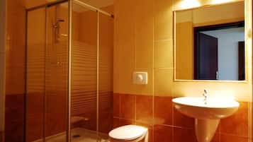 Ein Badezimmer mit Duschkabine, Toilette und Waschbecken mit Spiegel darüber.