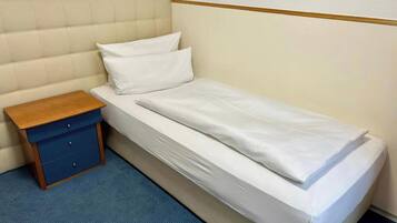 A single bed with a wooden nightstand and a blue drawer unit.