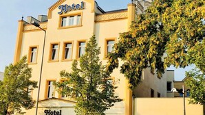 Un edificio di un hotel con un cartello ben visibile con la scritta 'Hotel' sulla facciata, diverse finestre e un albero sullo sfondo.