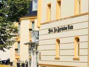 Hotel Am Bayrischen Platz with a classic facade, a visible entrance, and a balcony with chairs.