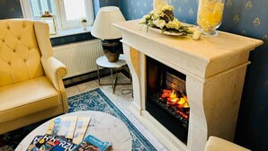 Un accogliente soggiorno con camino, divano, tavolino da caffè con riviste e vasi decorativi.