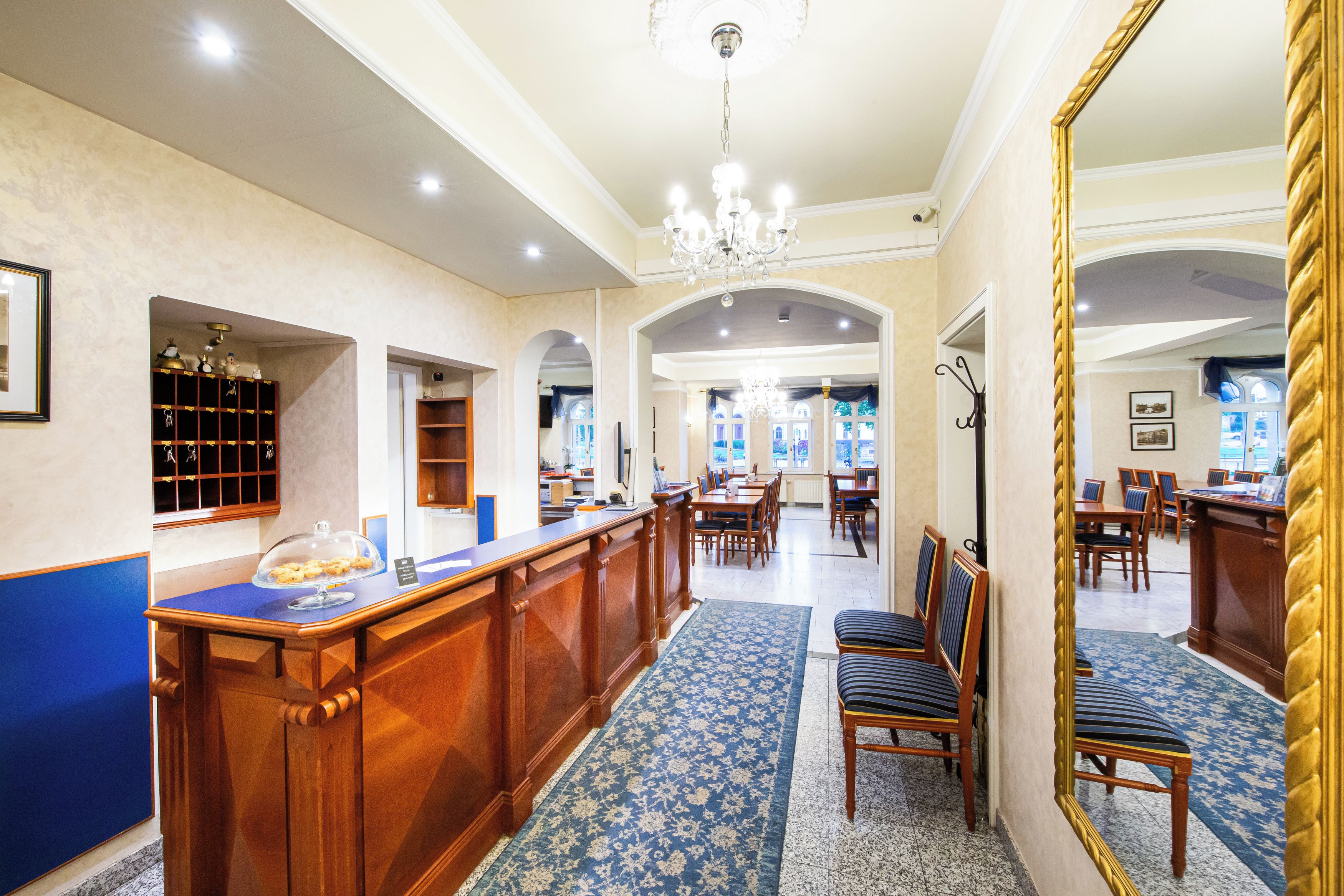Un hall de hotel con mostrador de recepción, zona de estar y un espejo grande.