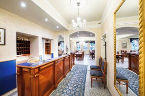A hotel lobby with a reception desk, seating area, and a large mirror. - Hotel am Bayrischen Platz (Leipzig)