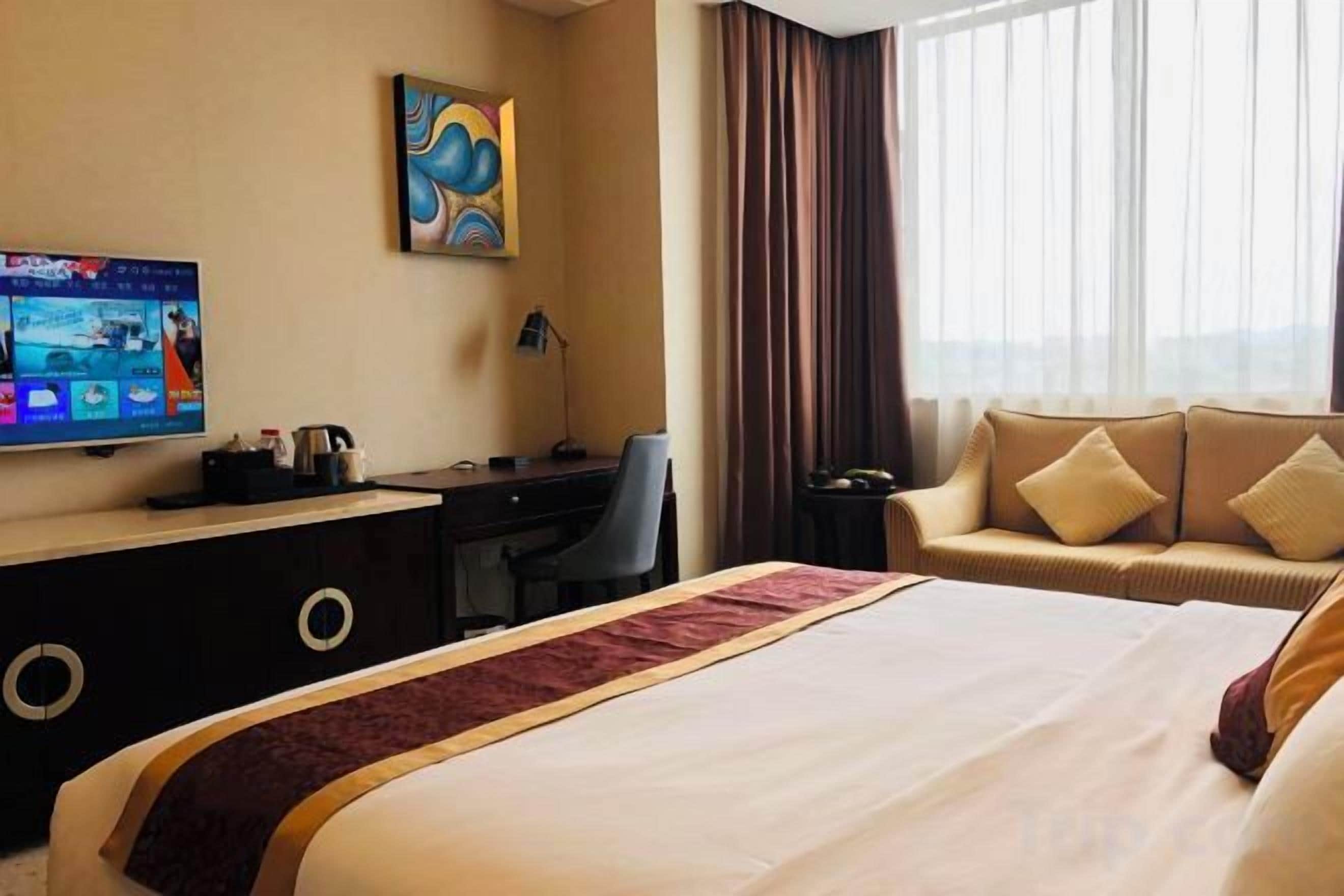 Une chambre d’hôtel avec un lit, un bureau, une télévision et une fenêtre avec des rideaux.