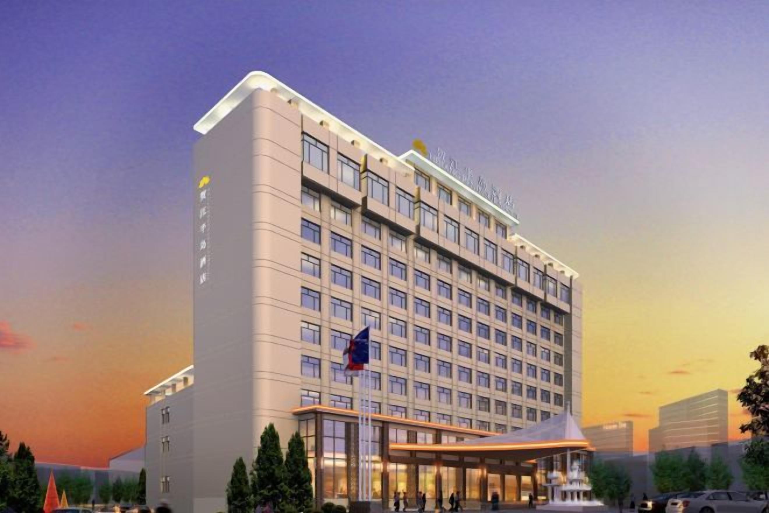 A modern hotel with a large number of rooms, a prominent entrance, and a flag.