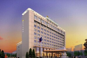 A modern hotel with a large number of rooms, a prominent entrance, and a flag. - Hejiang Peninsula Hotel (Fengkai)