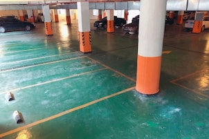 Un estacionamiento con varios niveles, plazas delimitadas y pilares anaranjados y blancos.