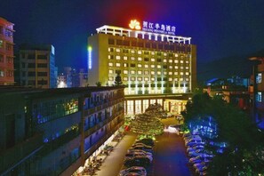 A hotel with a large building, multiple floors, and a well-lit facade.