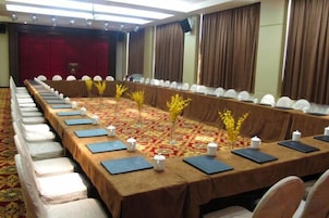 Un salón de conferencias con una mesa larga, sillas y piso alfombrado.