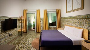 Una habitación de hotel con una cama, televisión, escritorio y una silla.