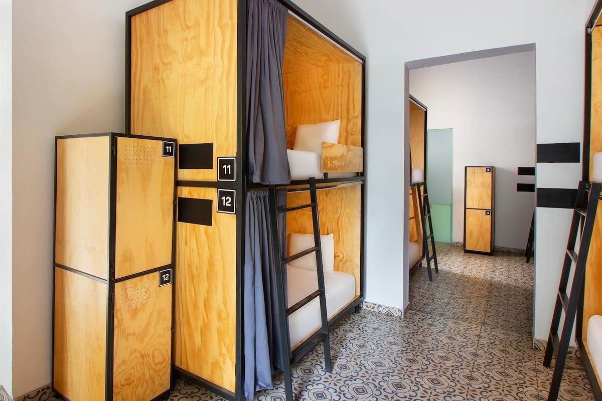 A hotel room with bunk beds, wooden headboards, and a patterned floor.