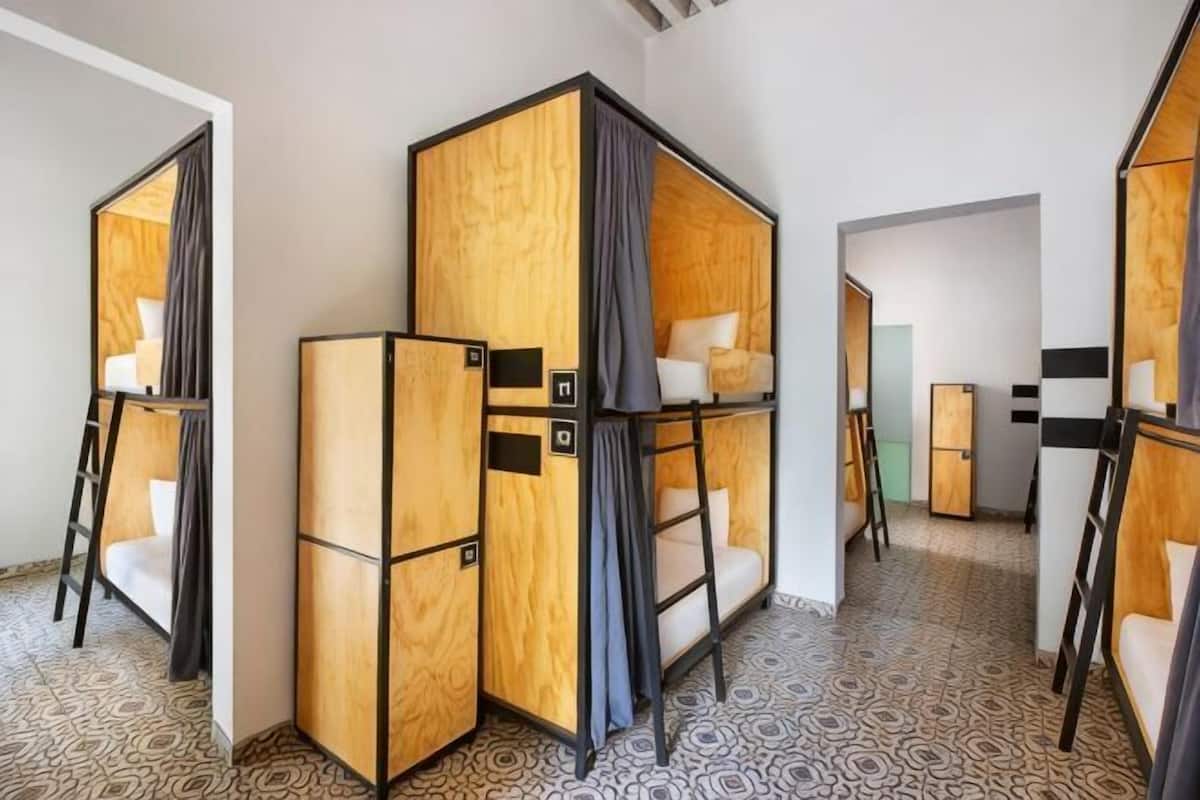 A hotel room with bunk beds, a small desk, and a chair.