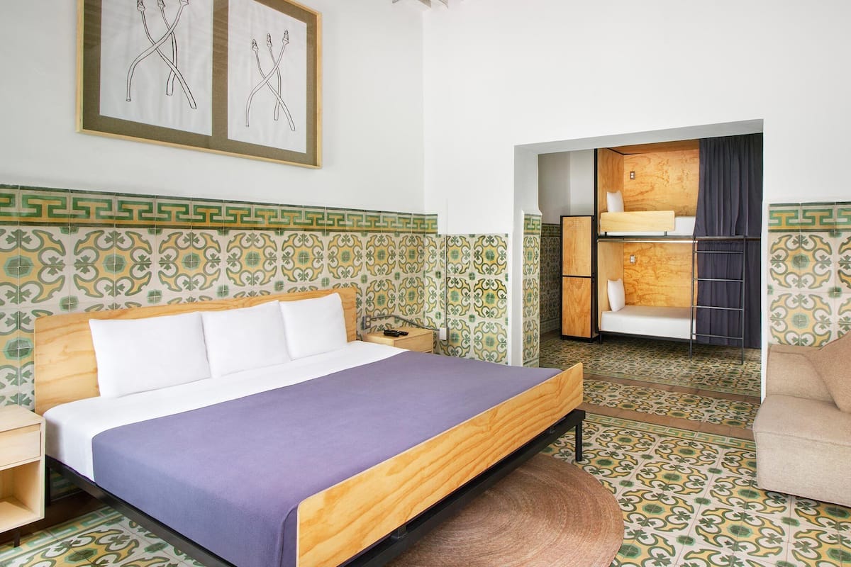 A hotel room with a bed, a nightstand, a chair, and a small table.