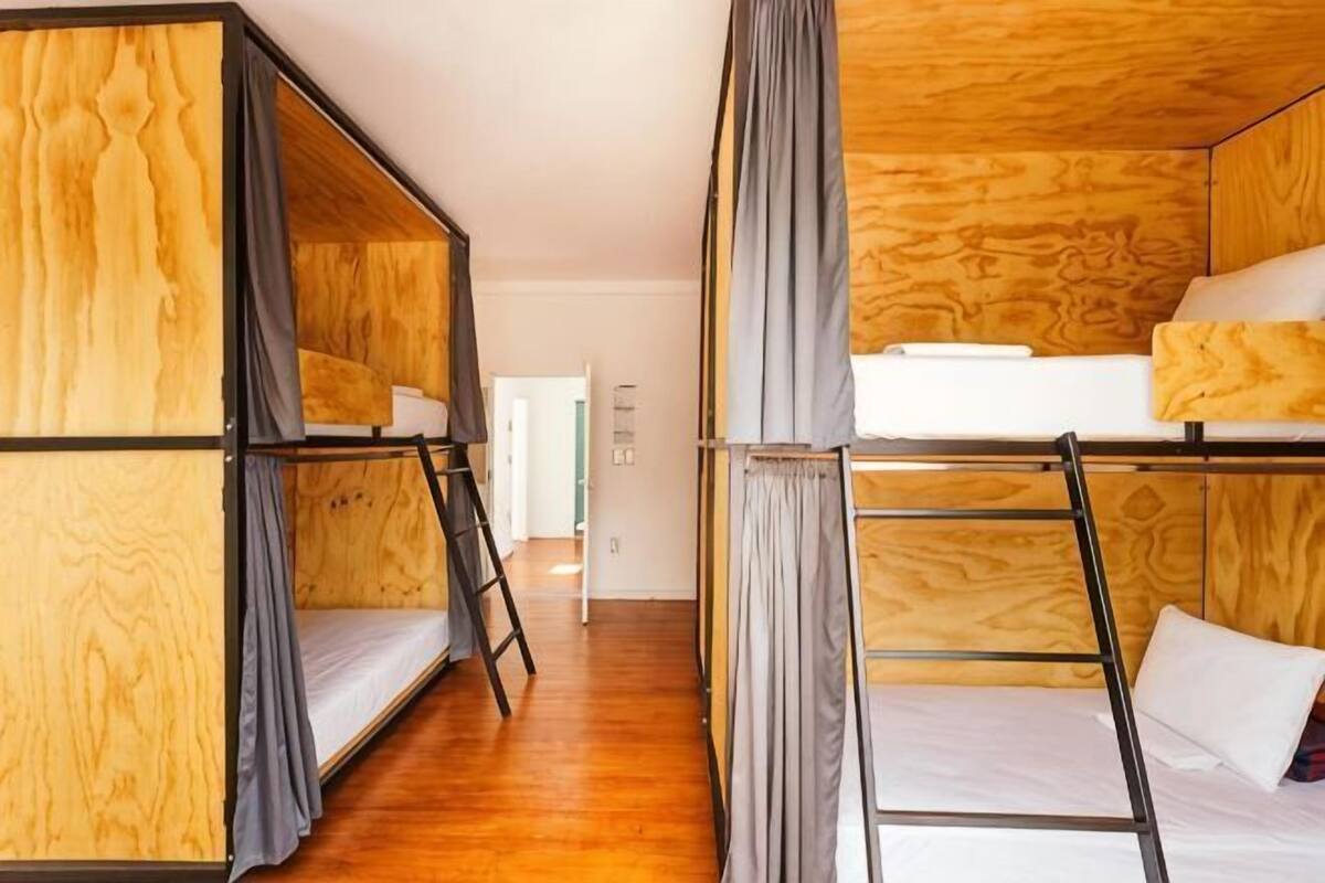 A room with bunk beds, wooden walls, and a corridor leading to another room.