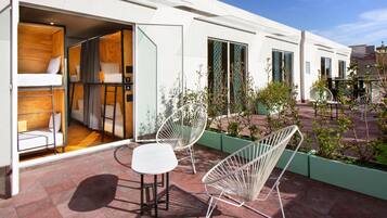 Ein modernes Hotelzimmer mit Balkon, einem weißen Sofa und zwei weißen Sesseln.