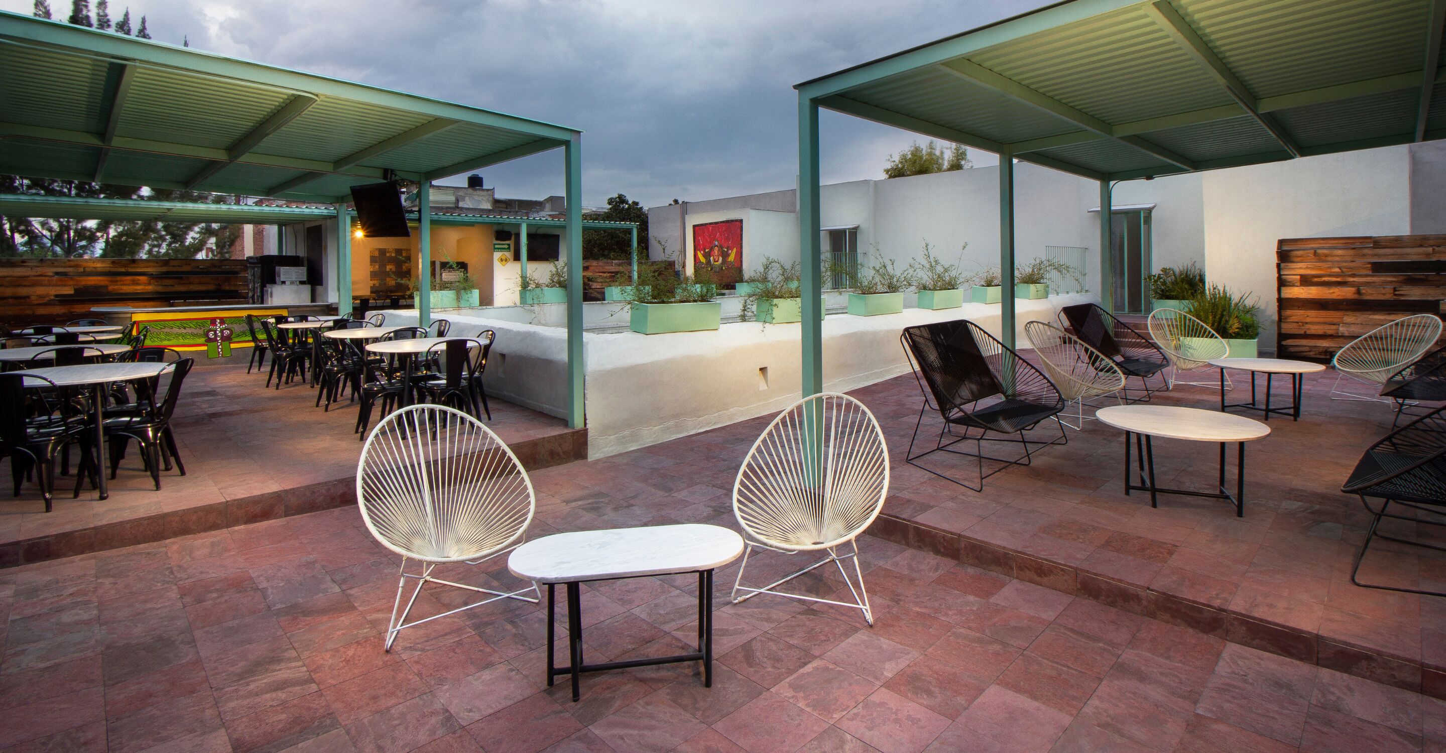 An outdoor patio area with multiple seating arrangements, including tables and chairs, under a covered roof.