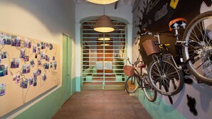 Un pasillo con una pared decorada con fotos, una bicicleta y una escalera con barandilla verde.