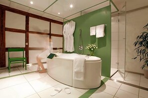 Un baño moderno con una bañera curvada, una silla verde y zona de ducha.