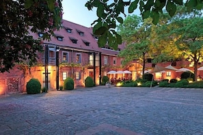 A courtyard with a brick building, outdoor seating, and greenery.